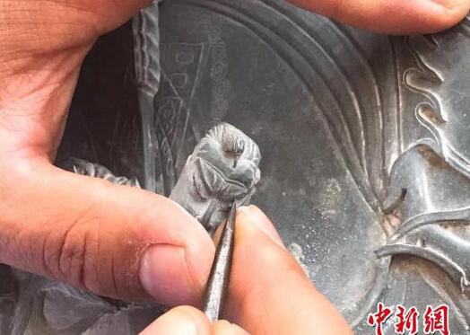 圖為馬萬榮將原本冰涼普通的洮河綠石雕刻成栩栩如生的山水人物圖案。